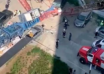 Строительный кран с рабочим внутри упал на автомобили в Новосибирске